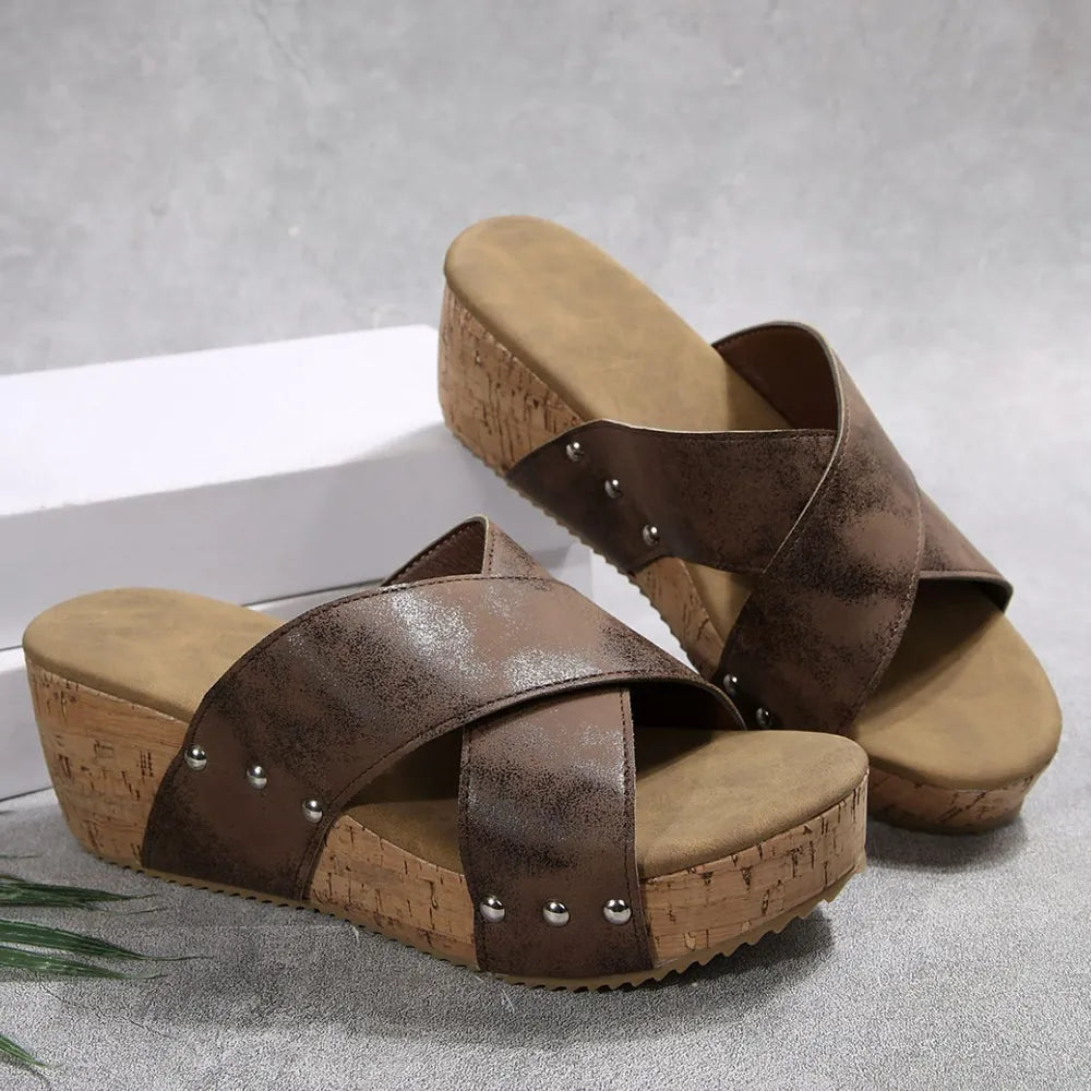 Brown crisscross cork wedge slides with silver stud details.