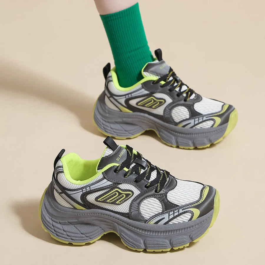 Chunky retro runner sneakers in white with grey and neon yellow accents, featuring a thick sole.
