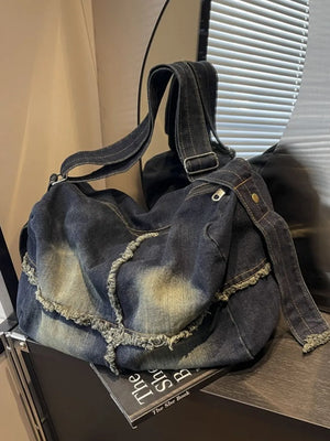 Dark wash denim crossbody bag with frayed edges and slouchy silhouette