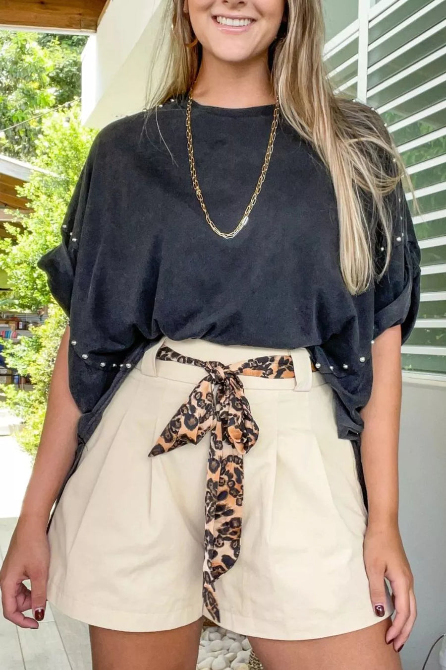 Black pearl-embellished t-shirt with wide-leg cream shorts and leopard print belt.