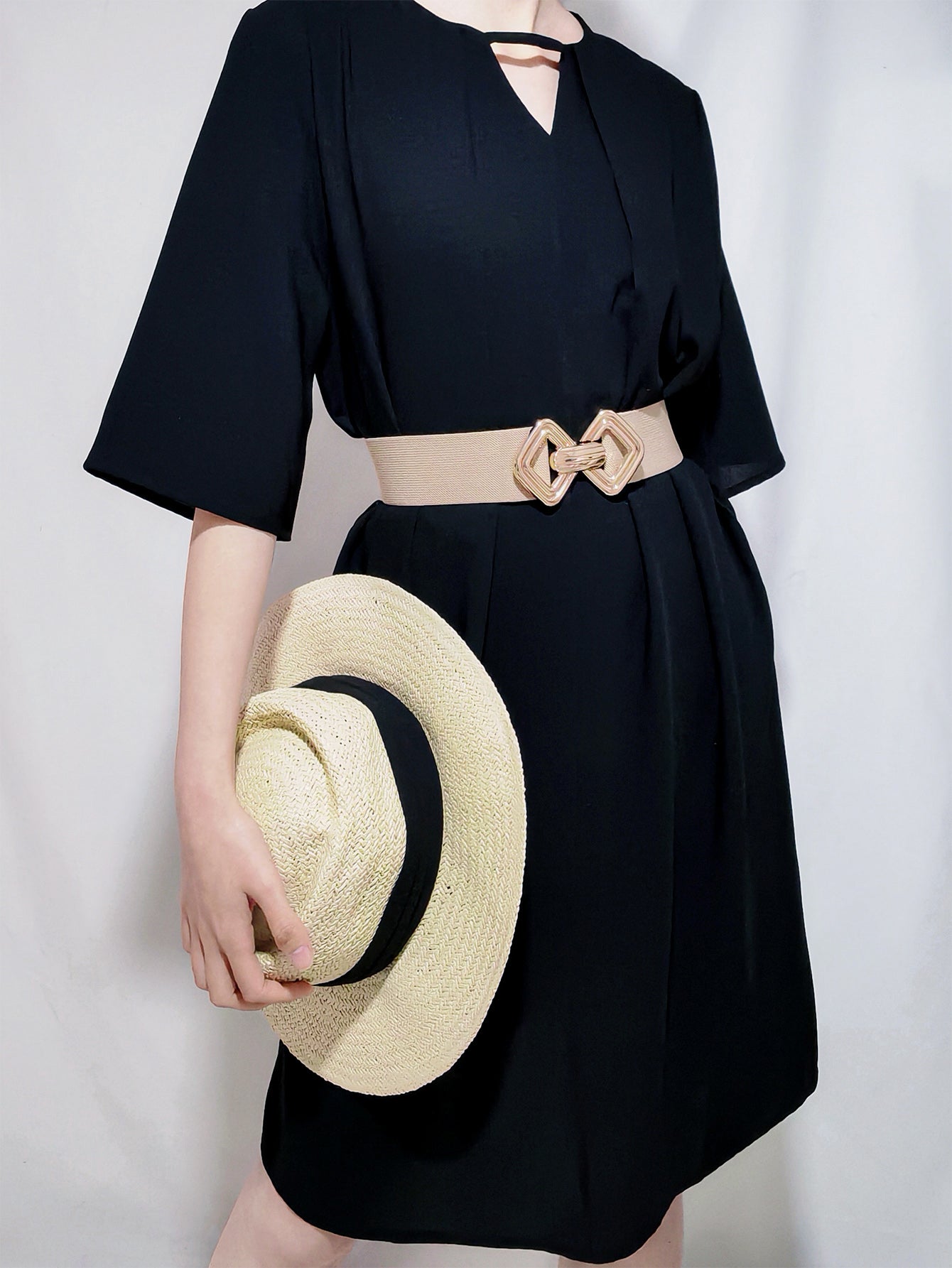 Elasticated waist belt in beige with geometric gold buckle, worn with a black dress.