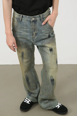Distressed medium wash carpenter jeans with paint-like smudges and a relaxed fit.