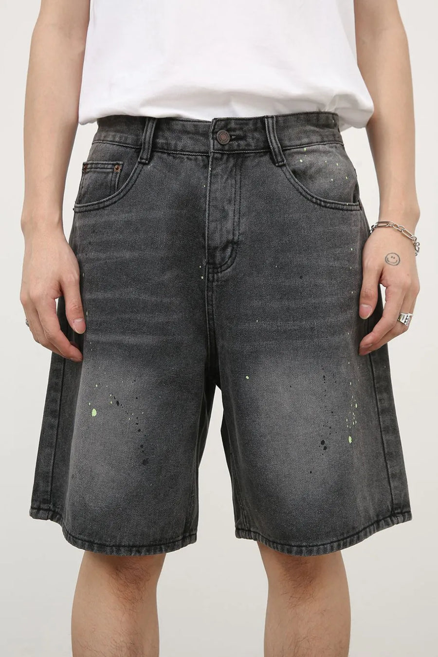 Dark wash denim bermuda shorts with artistic paint splatter detail