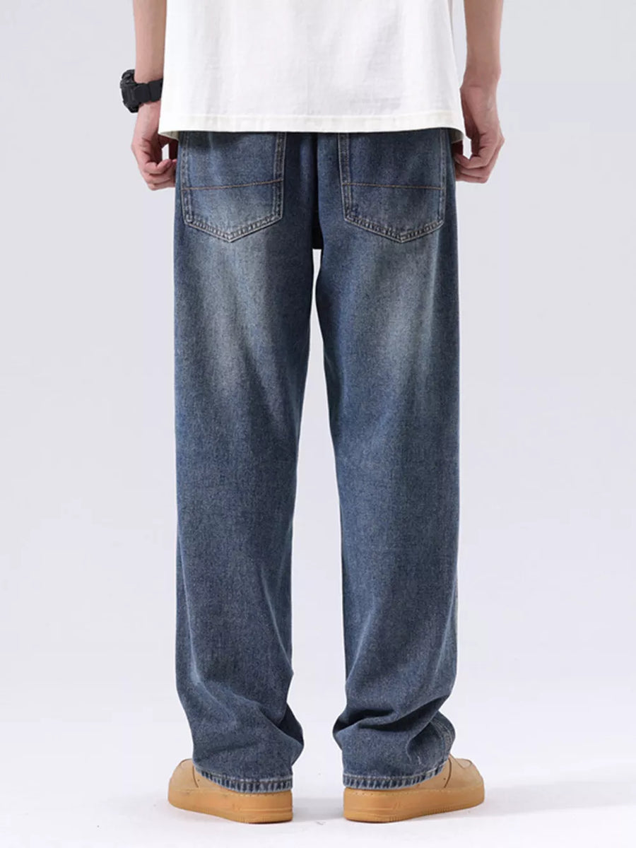 Men's blue vintage wash loose fit jeans with distressed detailing.