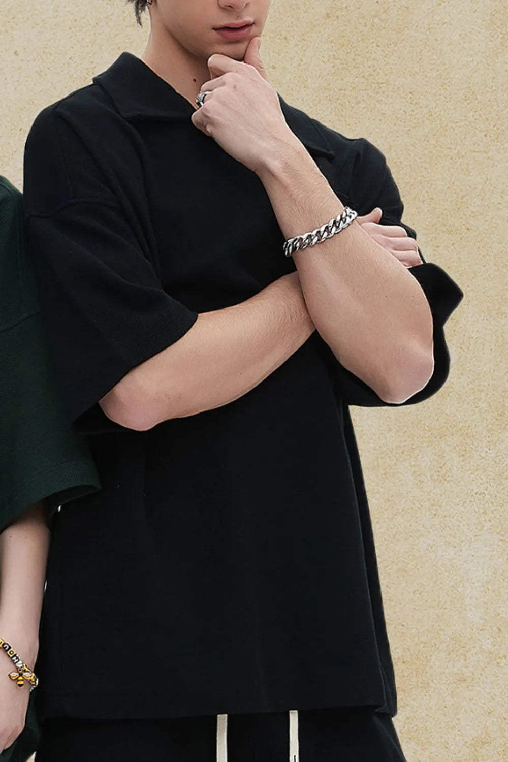 Black boxy knit polo with short sleeves and a patch pocket detail.