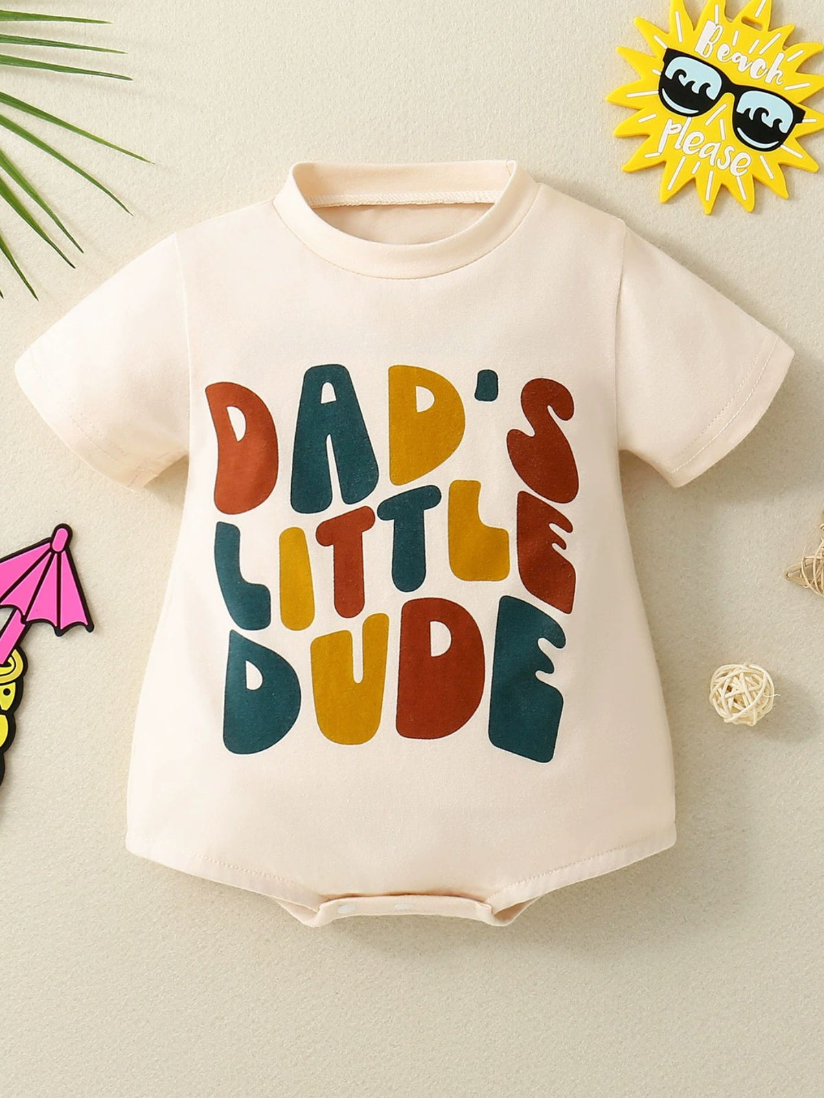 Baby bodysuit in beige with colorful "Dad's Little Dude" graphic print, short sleeves