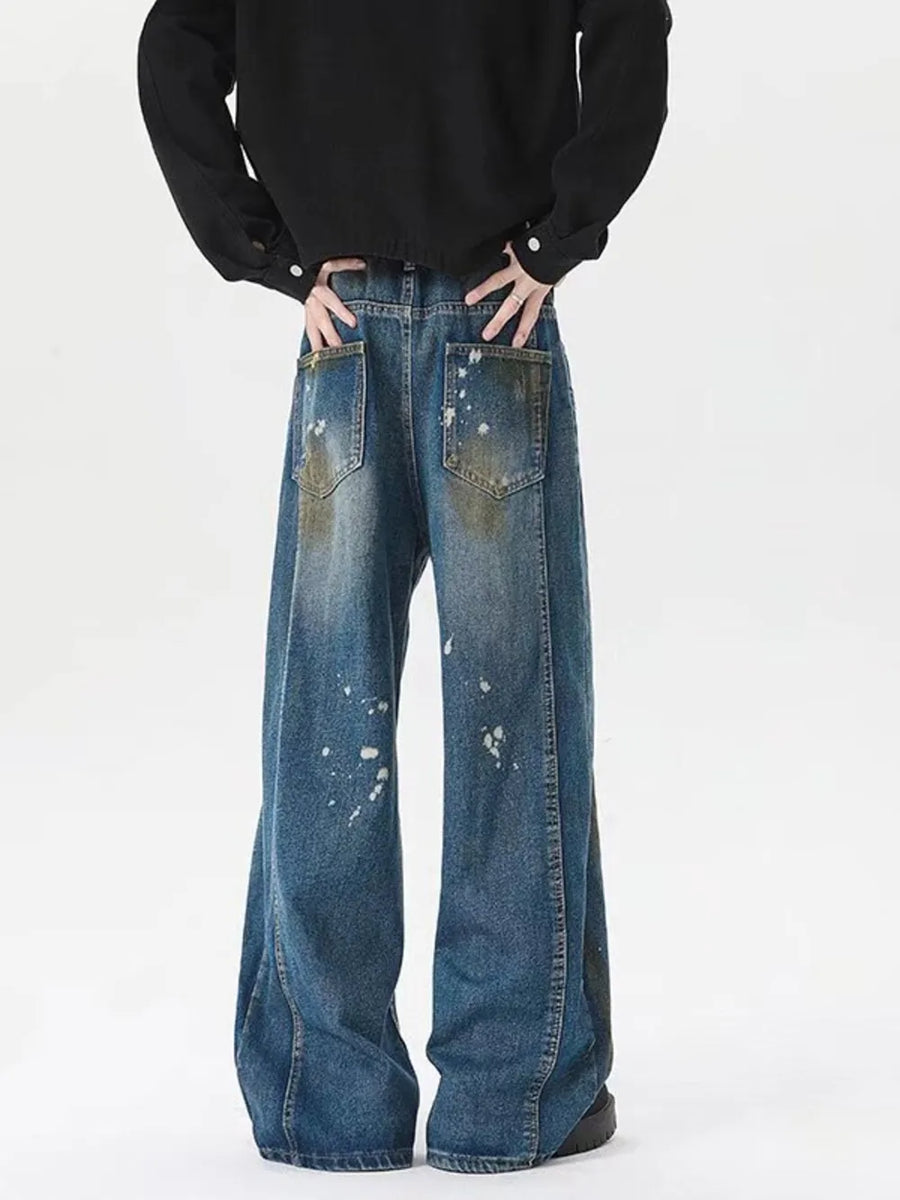 Men's plus-size wide-leg jeans in washed blue denim with paint splatters and distressed pockets.