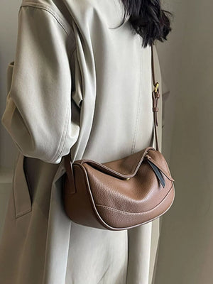 Brown pebbled leather crossbody bag with a flap closure and contrast piping detail.