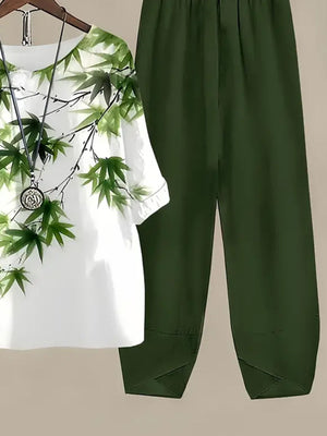 White floral print half sleeve top and dark green pants set with a necklace.