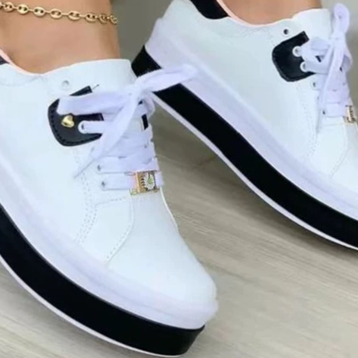 White lace-up platform sneakers with black accents and gold buckle detail.
