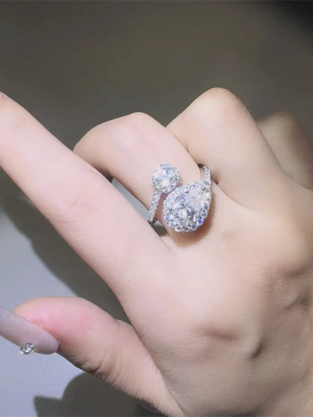 Silver bypass ring with two diamond halo clusters.