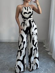 Elegant wide-leg jumpsuit with abstract black and white print, halter neck, and tie waist.
