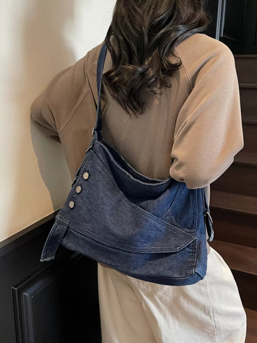 Relaxed denim crossbody bag with button accents and adjustable strap.