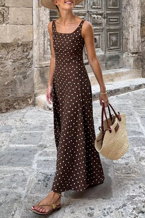 Brown polka dot maxi dress with square neckline and thin straps, worn with sandals and straw bag.