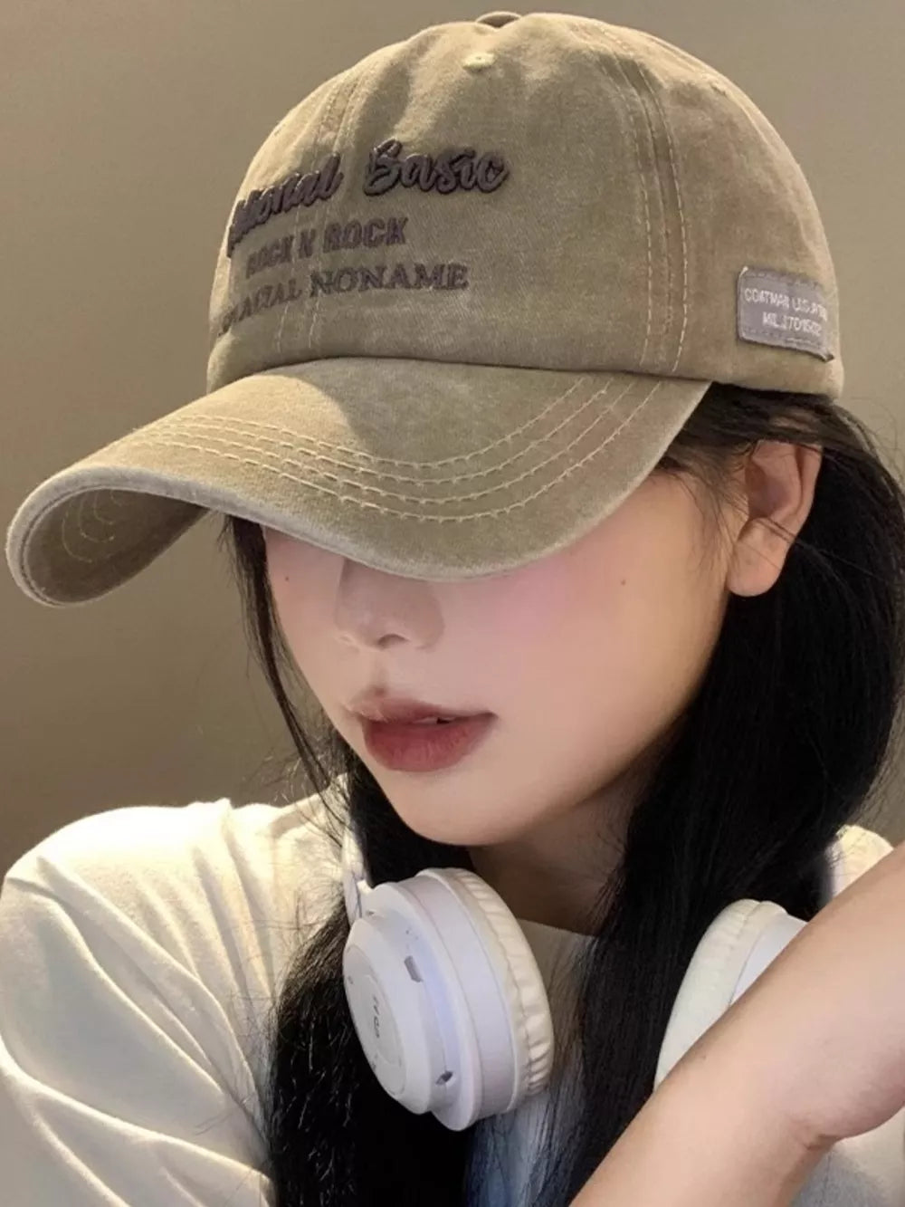 Khaki washed baseball cap with embroidered text and a patch detail.