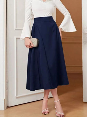 Navy high-waisted midi skirt with a flared A-line cut, styled with a white bell-sleeve top.