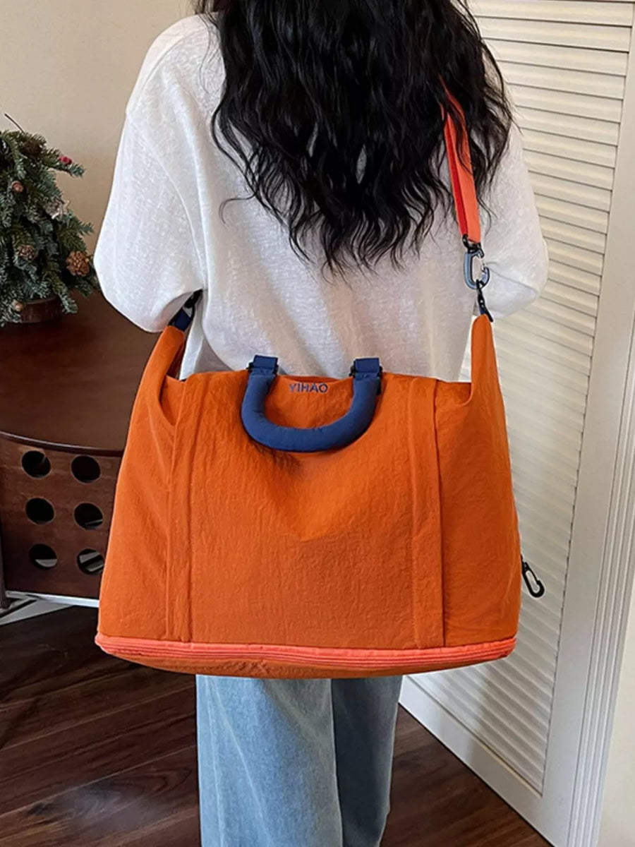 Spacious orange Oxford cloth travel bag with blue handles and strap, perfect for toiletries.