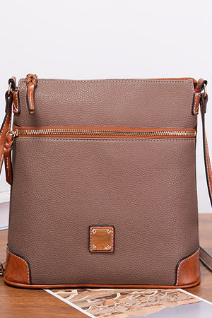 Taupe leather crossbody bag with brown trim and gold hardware.