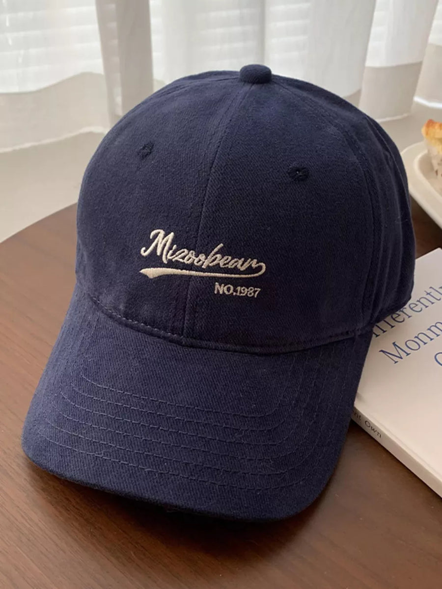 Navy blue cotton baseball cap with embroidered white lettering and curved brim.