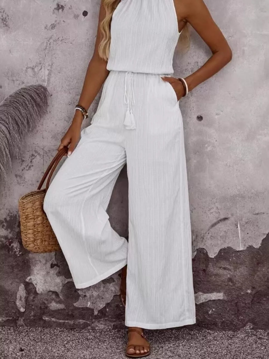 White crinkled wide-leg jumpsuit with tassel drawstring and halter neck.