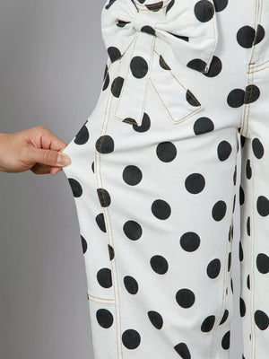 White polka dot high-waisted jeans with bow detail and tan stitching.