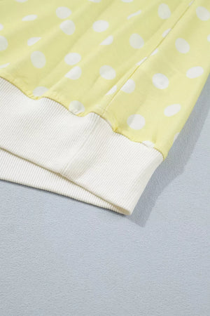 Pastel yellow polka dot top with white ribbed cuffs and hem detail.