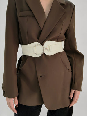 White cincher belt with silver ring buckle detail over a brown blazer
