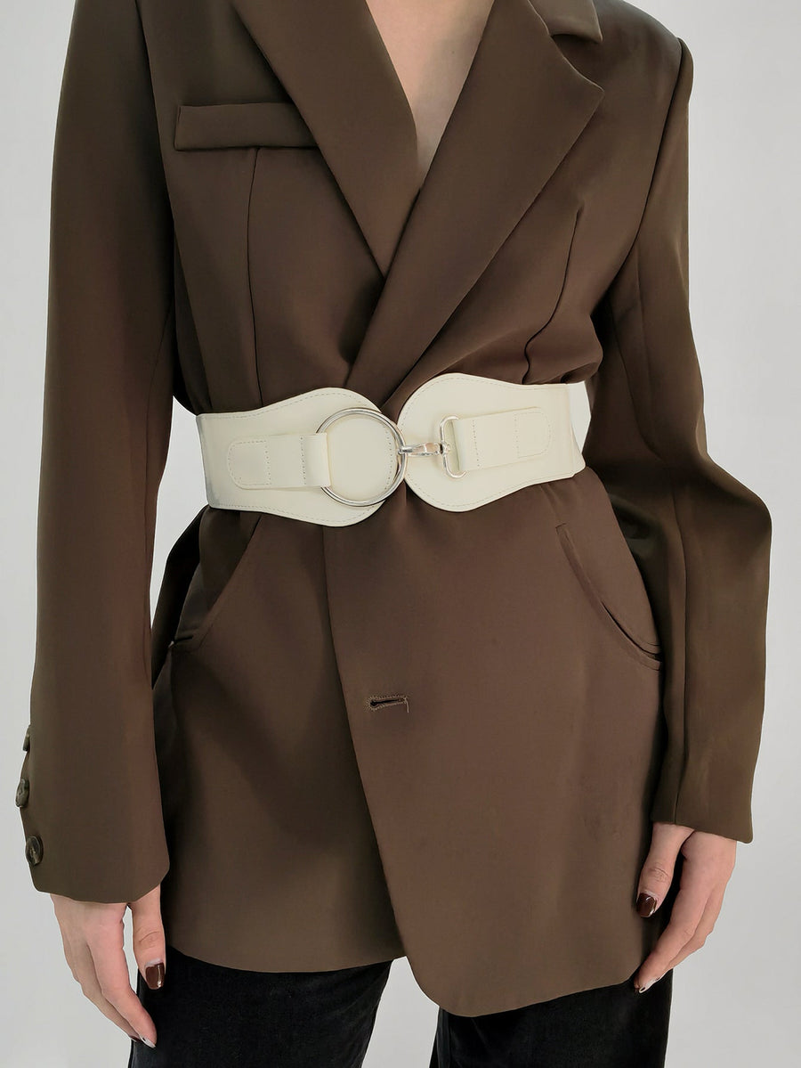 White cincher belt with silver ring buckle detail over a brown blazer