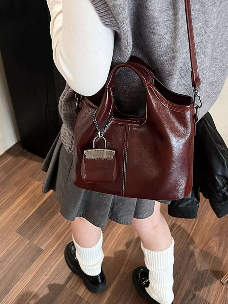 Chic red PU leather crossbody bag with chain detail and mini purse charm.