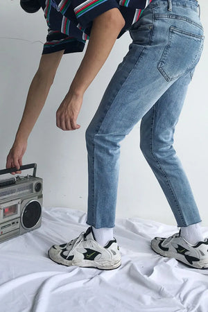 Raw hem slim-fit jeans in medium wash denim with a cropped length.