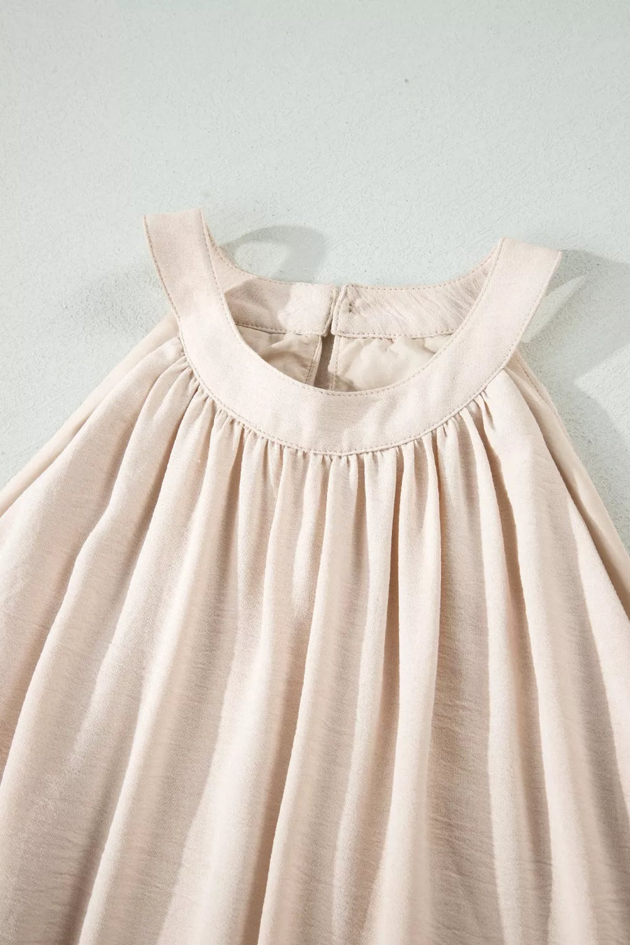 Beige halter maxi dress with gathered neckline and airy fabric.