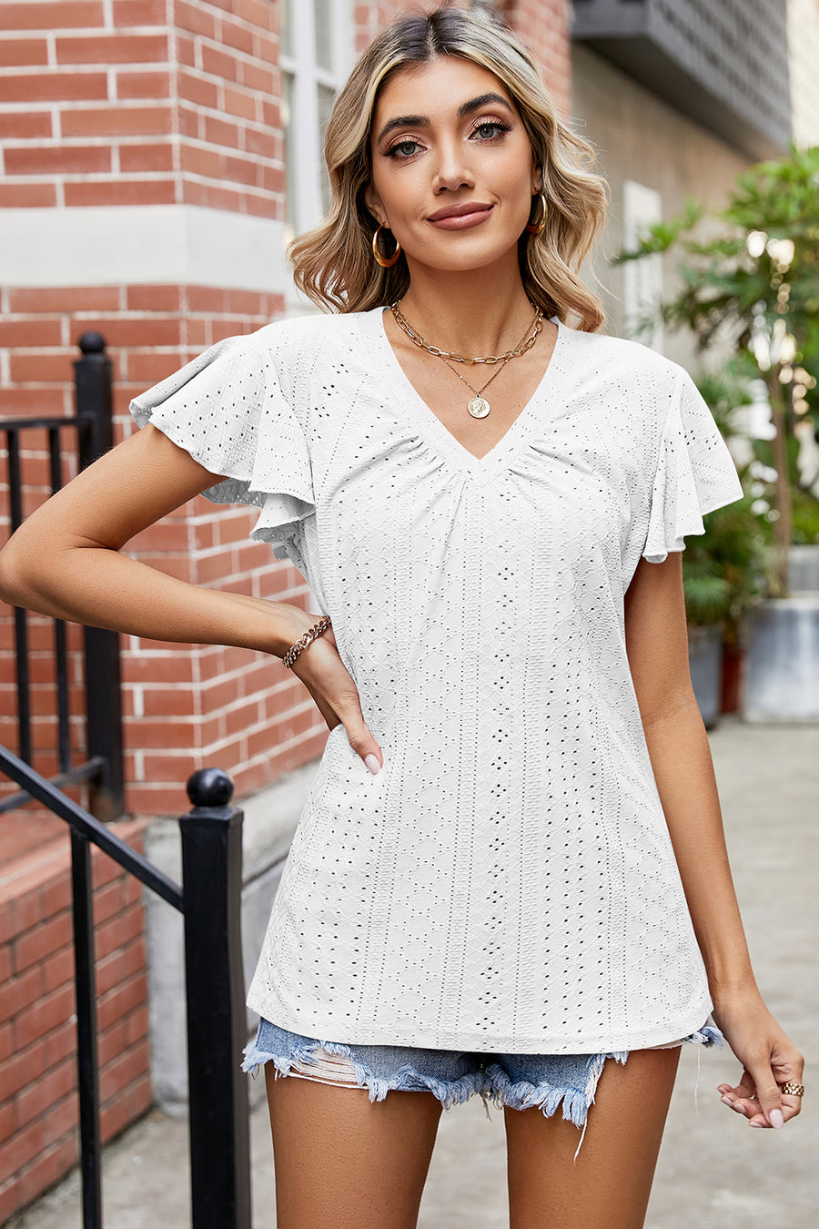 White eyelet flutter sleeve blouse with V-neck and ruched detail.
