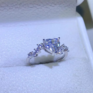 Silver ring with a heart-cut diamond cluster and smaller accent diamonds.