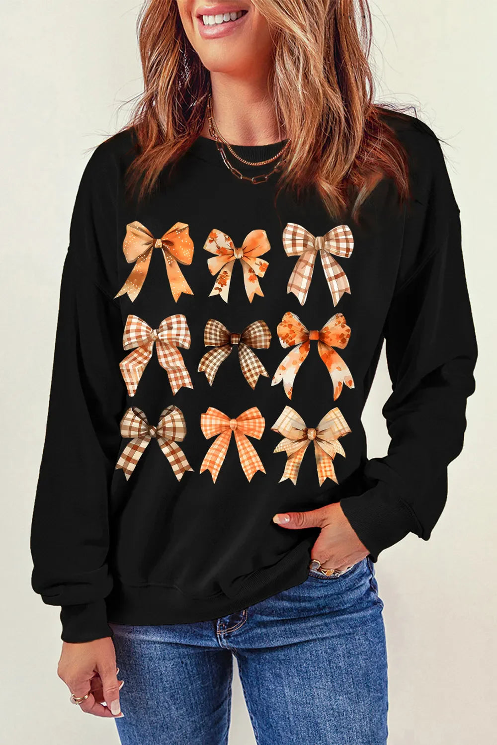 Black crewneck sweatshirt with a scattered bow print in autumn colors.