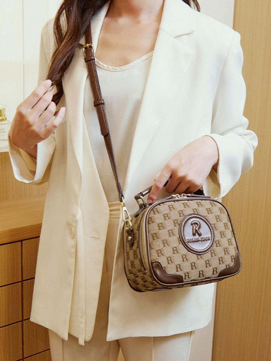 tan crossbody bag featuring top handle and monogram
