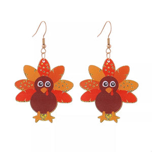 Festive turkey dangle earrings in red, orange, and yellow acrylic with gold accents.