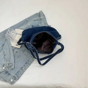 Denim hobo bag with leatherette patch and adjustable strap, shown with a denim jacket.