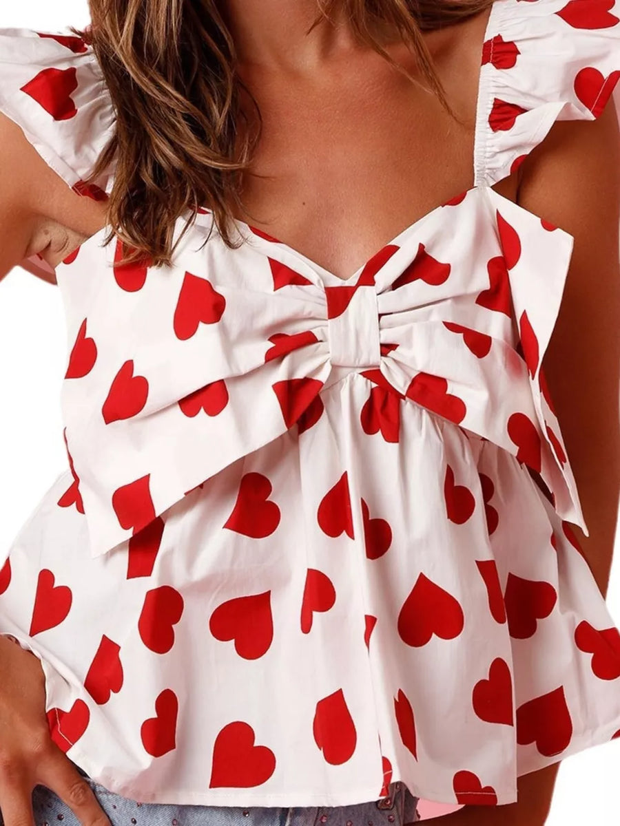 White tank top with red hearts, ruffle trim, and a bow detail.