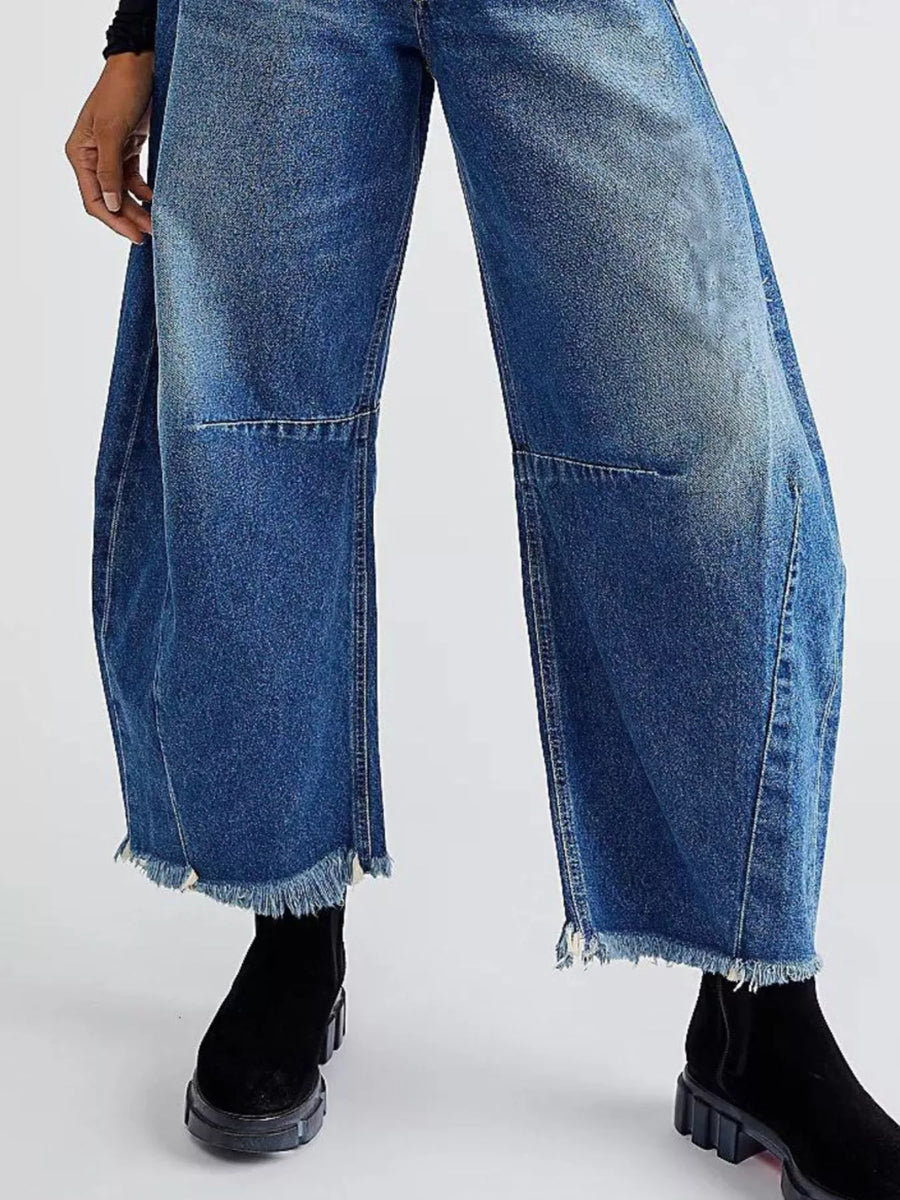 Blue wide-leg denim trousers with raw hem and panel detail.