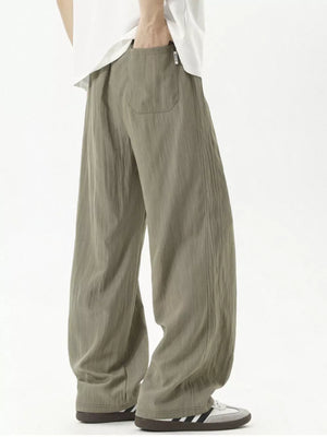 Men's khaki track pants with vertical texture and back pocket detail.