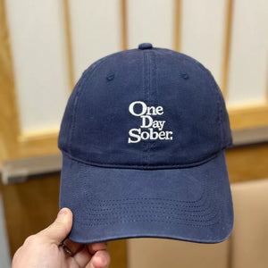 Navy baseball cap with white embroidered "One Day Sober" text