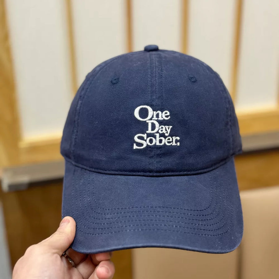 Navy baseball cap with white embroidered "One Day Sober" text