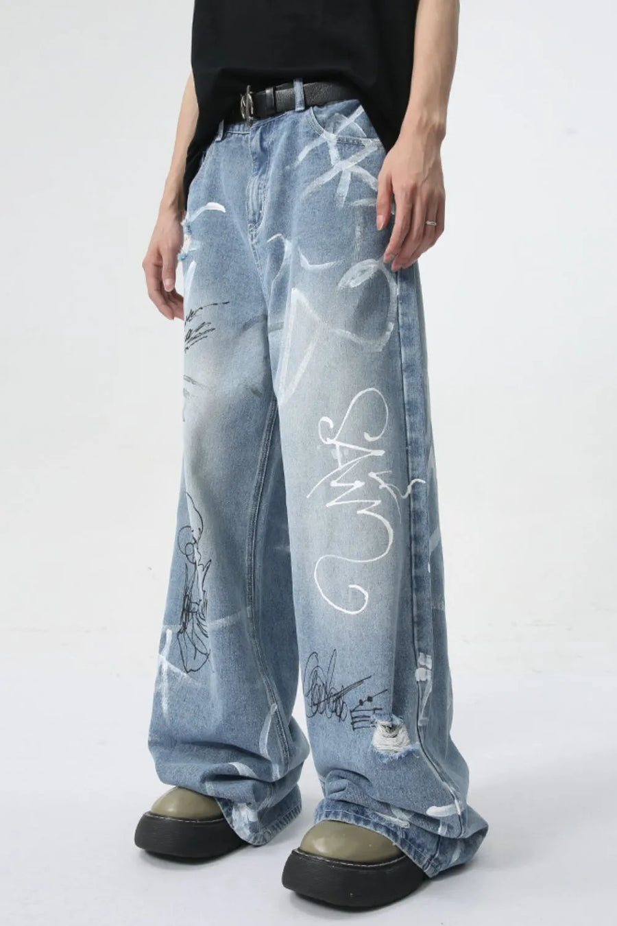Graffiti art oversized denim trousers in medium wash with distressed details and white graphic print.