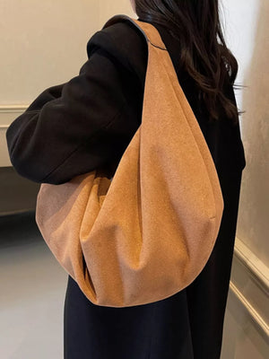 Spacious yellow brown suede shoulder bag with slouchy design and zipper pocket detail.