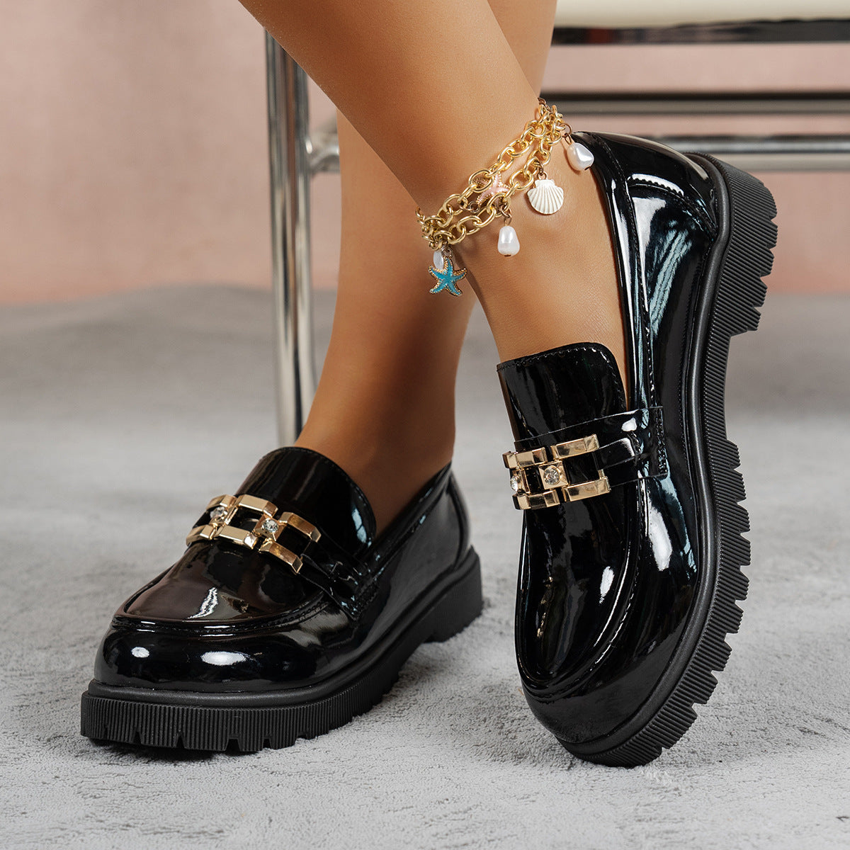Black patent leather chunky loafers with gold buckle detail and lug sole.