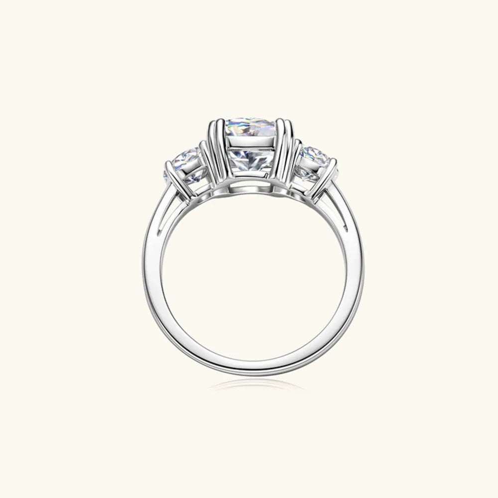 Silver three-stone cushion cut moissanite ring with a solitaire center stone and two smaller side stones.