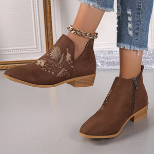 Brown suede ankle boots with floral embroidery and side zip detail.