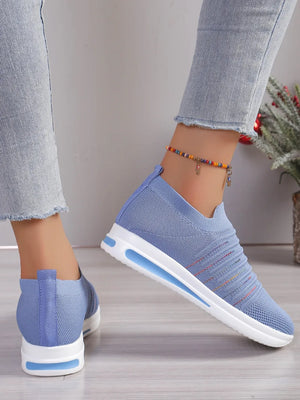 Light blue knit slip-on wedge sneakers with subtle striped detail and white soles.