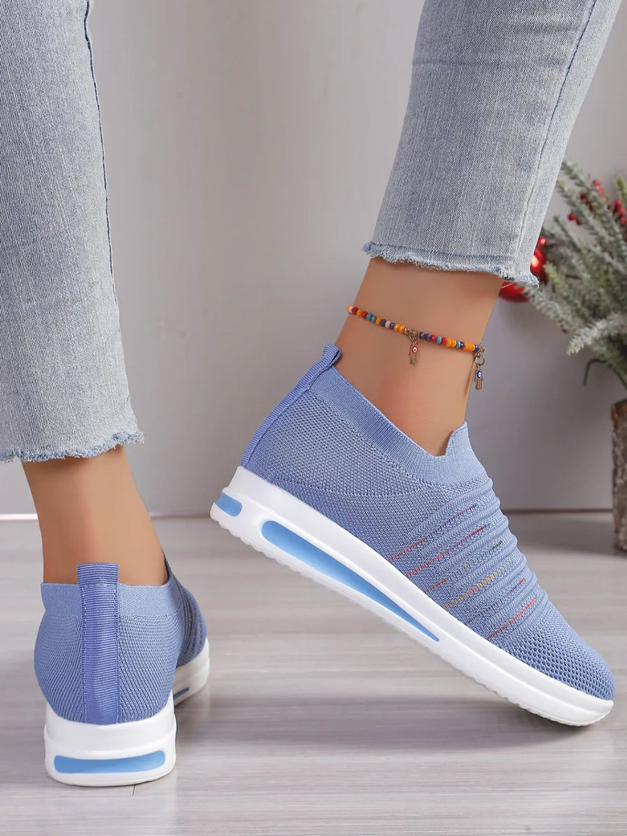 Light blue knit slip-on wedge sneakers with subtle striped detail and white soles.