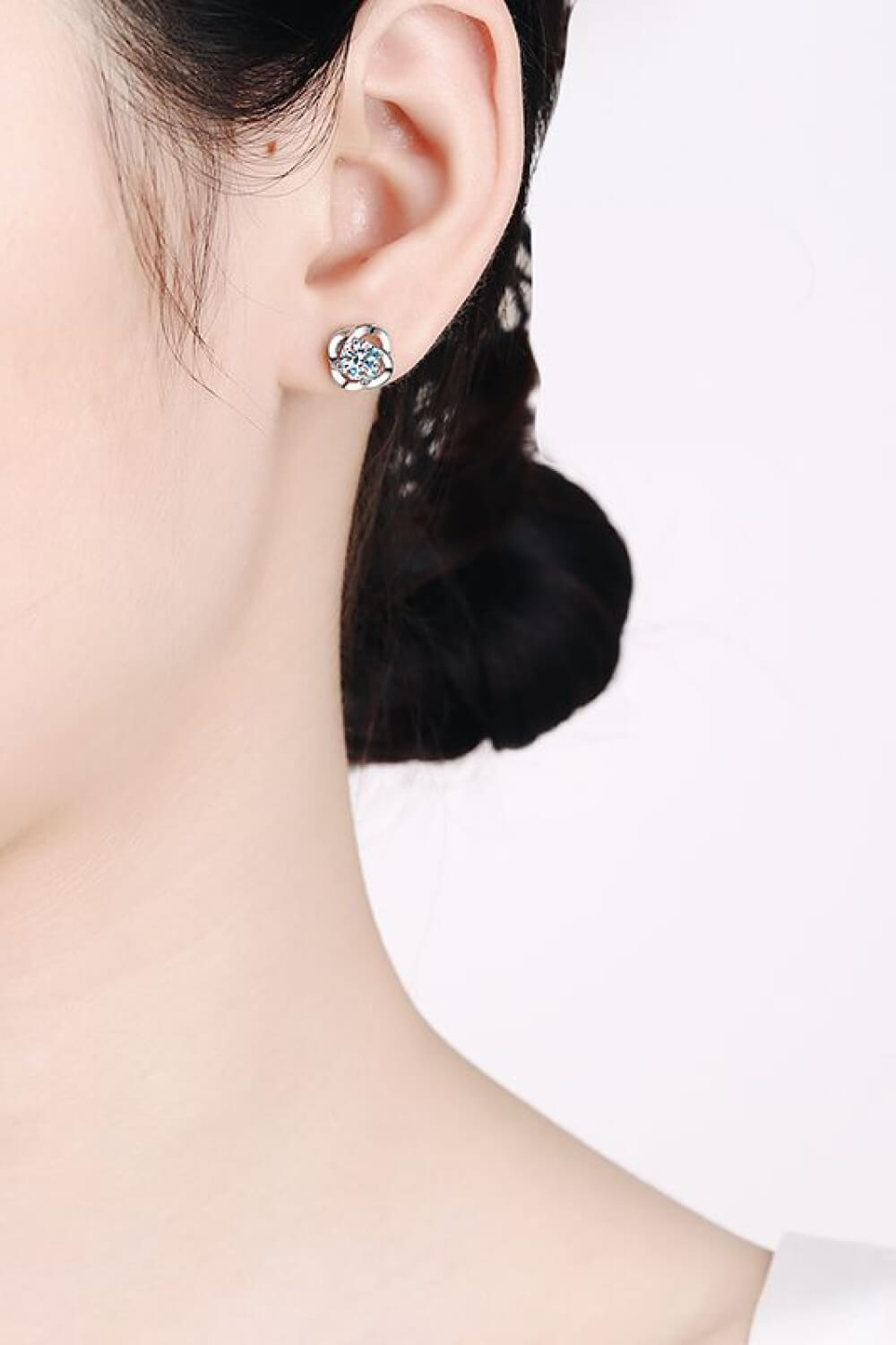Silver four-leaf clover stud earrings with a central sparkling stone.